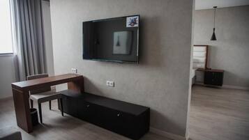 Una sala moderna con un televisor de pantalla plana montado en la pared, una mesa de comedor de madera y un banco negro.