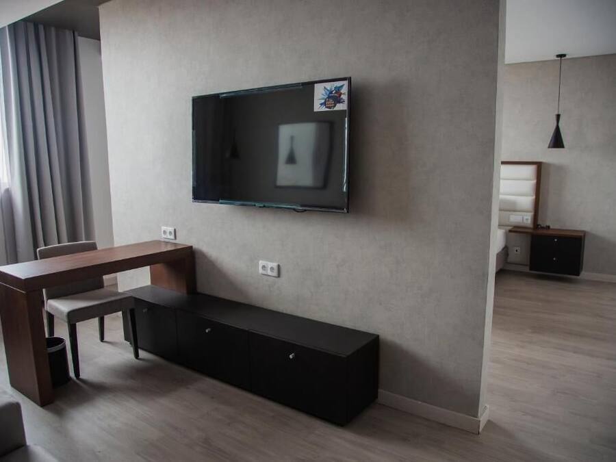 Una sala moderna con un televisor de pantalla plana montado en la pared, una mesa de comedor de madera y un banco negro.