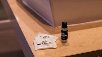 A bathroom sink with a white basin and a modern faucet. A bottle and a packet are placed on the countertop.