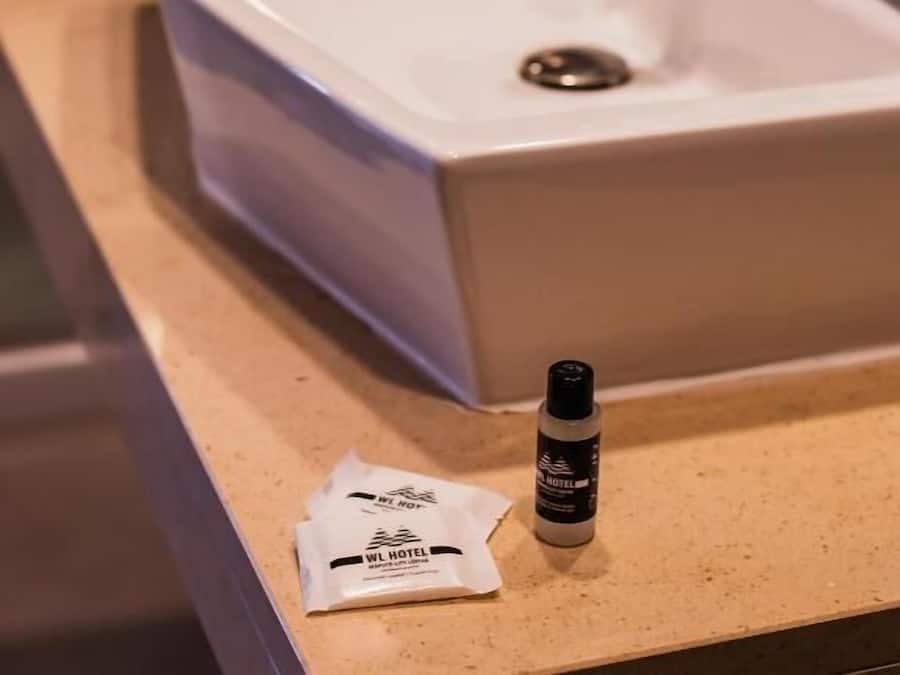 A bathroom sink with a white basin and a modern faucet. A bottle and a packet are placed on the countertop.