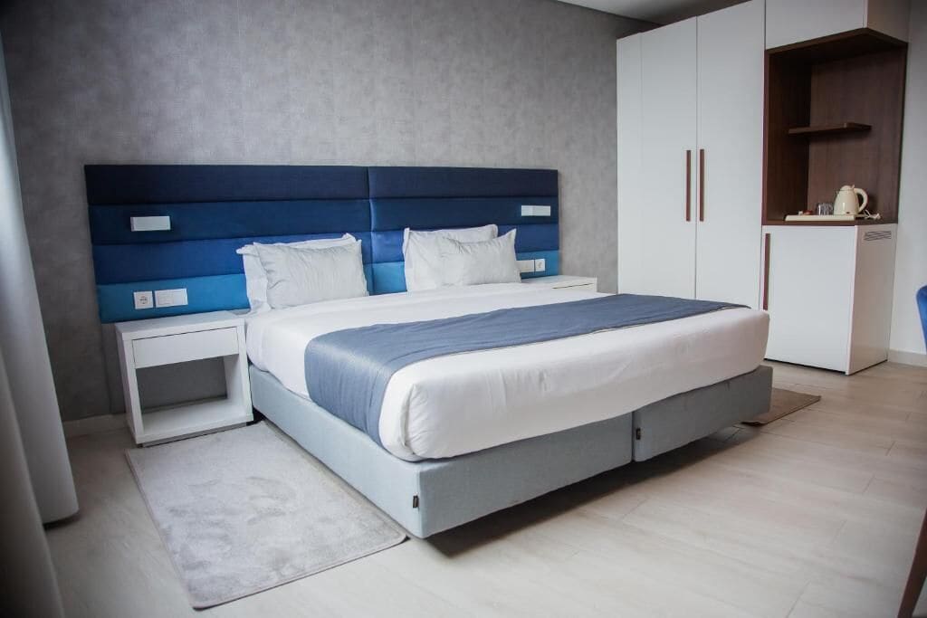 Un dormitorio moderno con cama, mesitas de noche y armario.