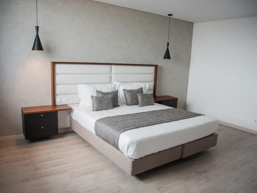 Une chambre moderne avec un grand lit, deux tables de chevet et des lampes suspendues.