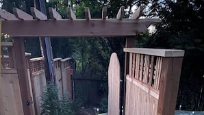 A wooden gate leading to a garden area with a paved path. - Private Daylight Basement | Near Downtown & Lake (Lake Oswego)