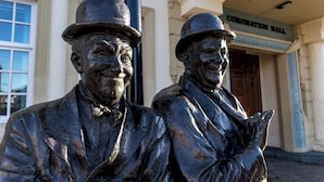 Two bronze statues of men in suits and hats in front of a building labeled "Coronation Hall". - Large House in Central Ulverston | Sleeps 10 - Pass the Keys (Ulverston)