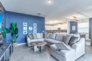 A modern living room with a gray sectional sofa, a round coffee table, and a large potted plant.