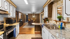 A kitchen with wooden cabinets, a microwave, a stove, and a sink. - Forest Cabin Near Sekiu Fish & Hunt Basecamp (Clallam County)