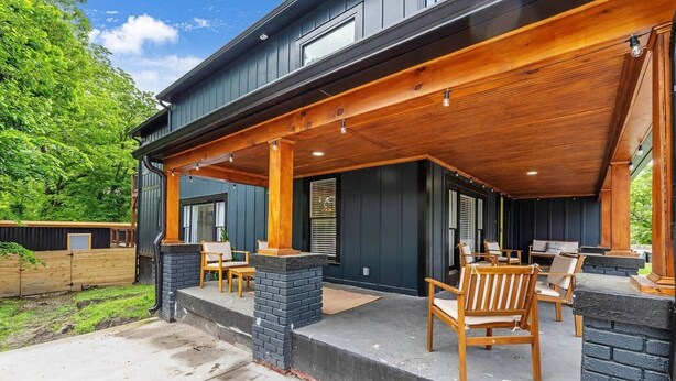 Un espacio de patio techado con muebles de madera y vistas al follaje circundante.