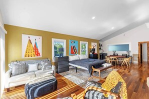 Una sala moderna con un sofá, una cama, un comedor y obras de arte en las paredes.