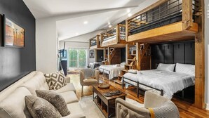 Un interior moderno con un entrepiso con cama, un conjunto de sofás y un comedor.