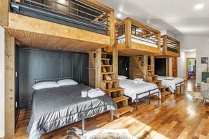 Una habitación con literas, escaleras de madera y suelo de madera.