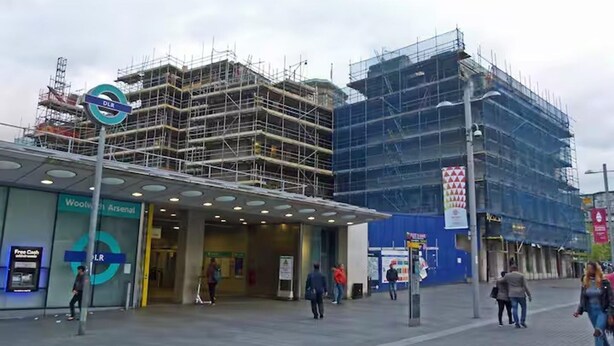 A building under construction with scaffolding, a Woolworths Arsenal store, and a sign for a free cash machine. - Cosy London Apartment Near River Thames (London)