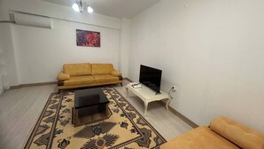 Un soggiorno con divano, tavolino, televisore e tappeto decorato.