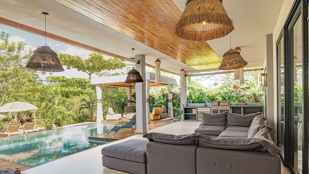 Zona d'estar exterior moderna amb piscina, seients i entorn natural.
