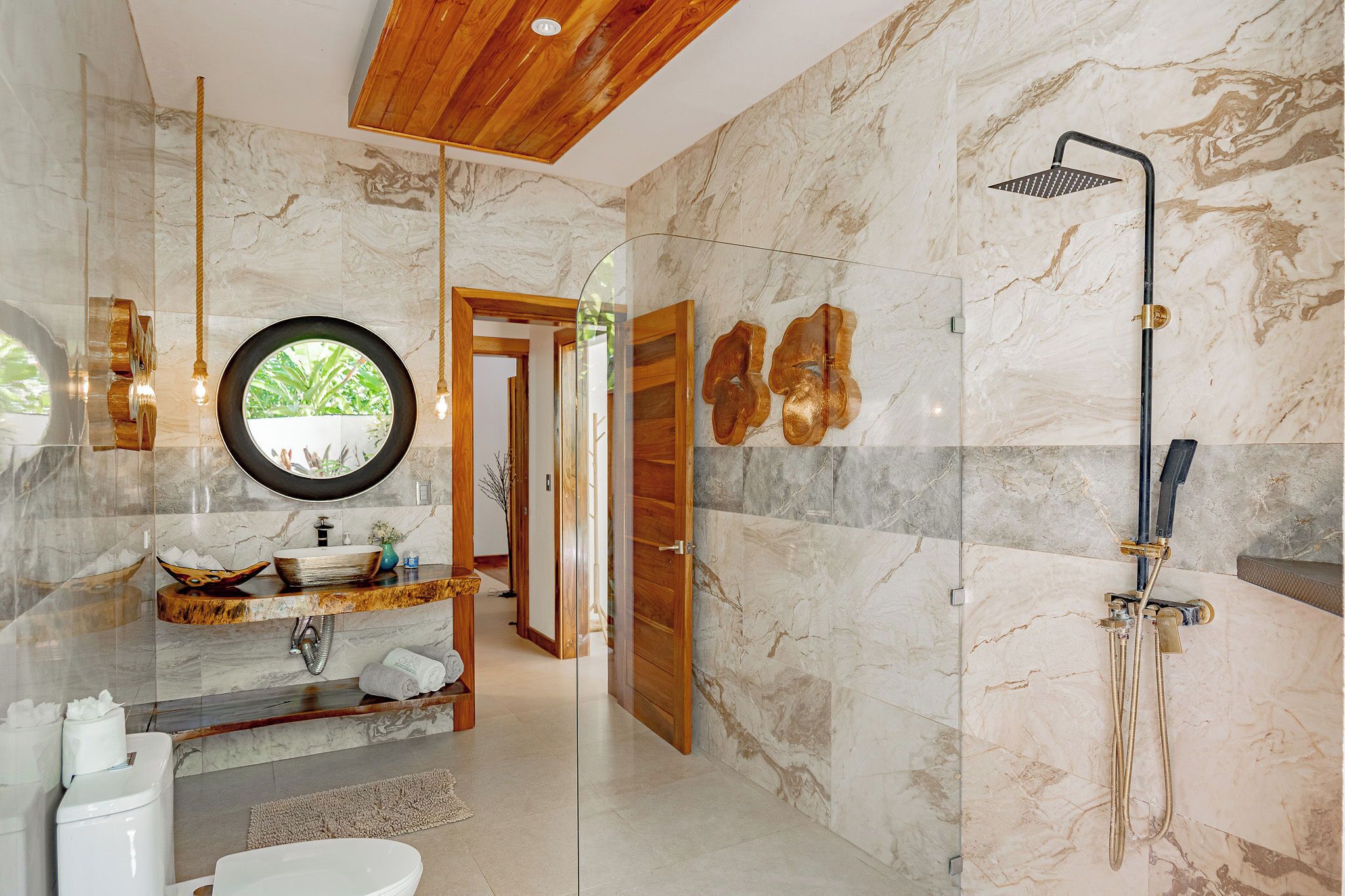 A modern bathroom with a glass-enclosed shower, a wooden vanity, and a marble-tiled floor.