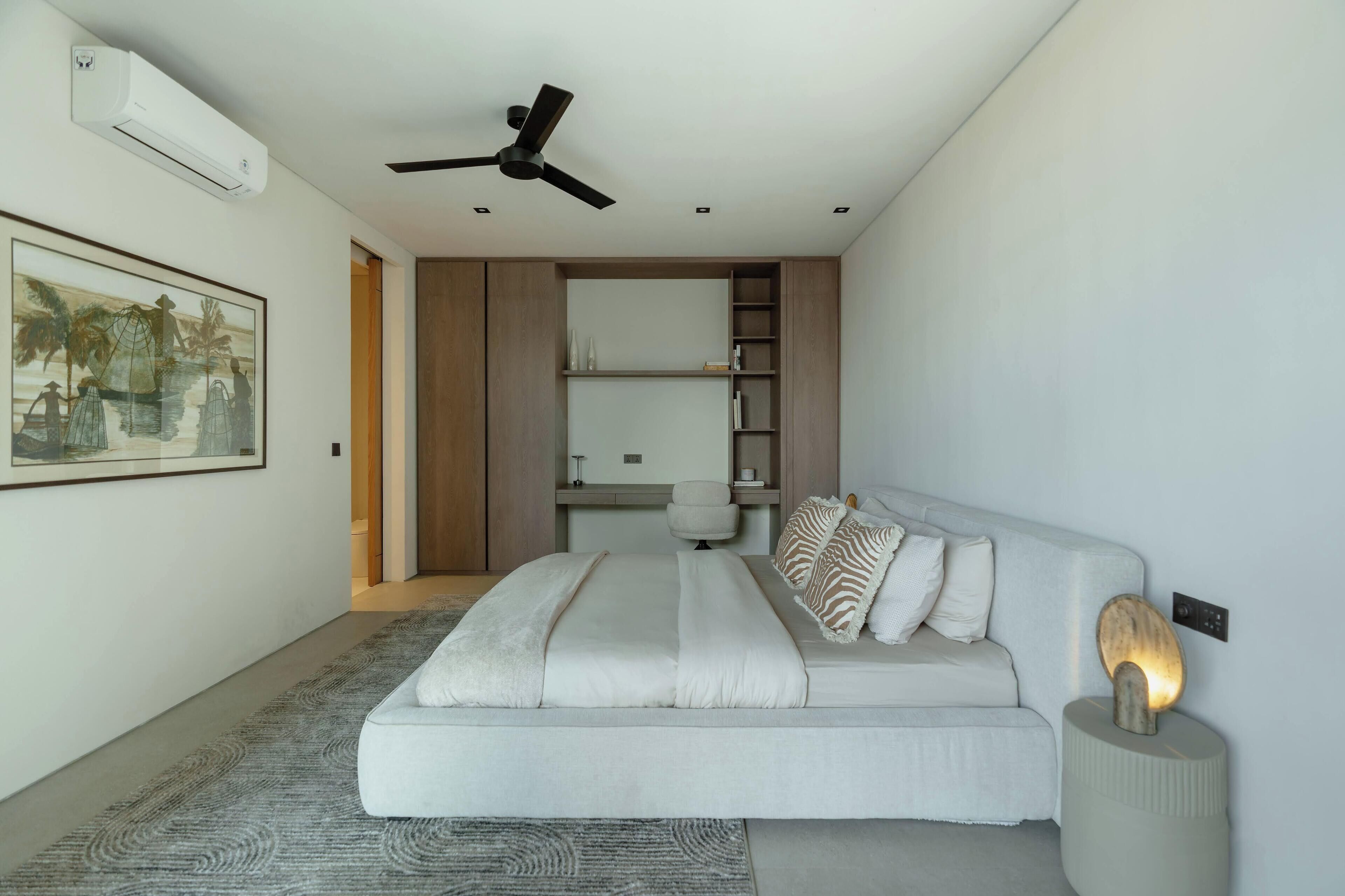 Un dormitorio moderno con una cama, un ventilador de techo, un escritorio y una estantería.