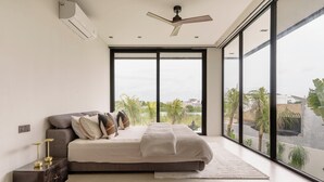 A modern bedroom with a large window, a bed, and a ceiling fan. - Ultra-Luxe 4BR Seminyak Villa | Enclosed AC Living & Private Pool (Seminyak)