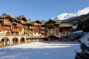 A multi-story wooden building with balconies, set against a snowy mountain backdrop. - 150m from ski slopes, 2nd floor, fitness, swimming pool, balcony, tv, ski locker, 30m², Val Cenis (Lanslebourg-Mont-Cenis)