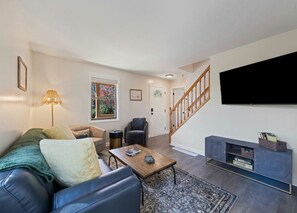 Ein Wohnzimmer mit einer Couch, einem Couchtisch und einem an der Wand befestigten Fernseher.