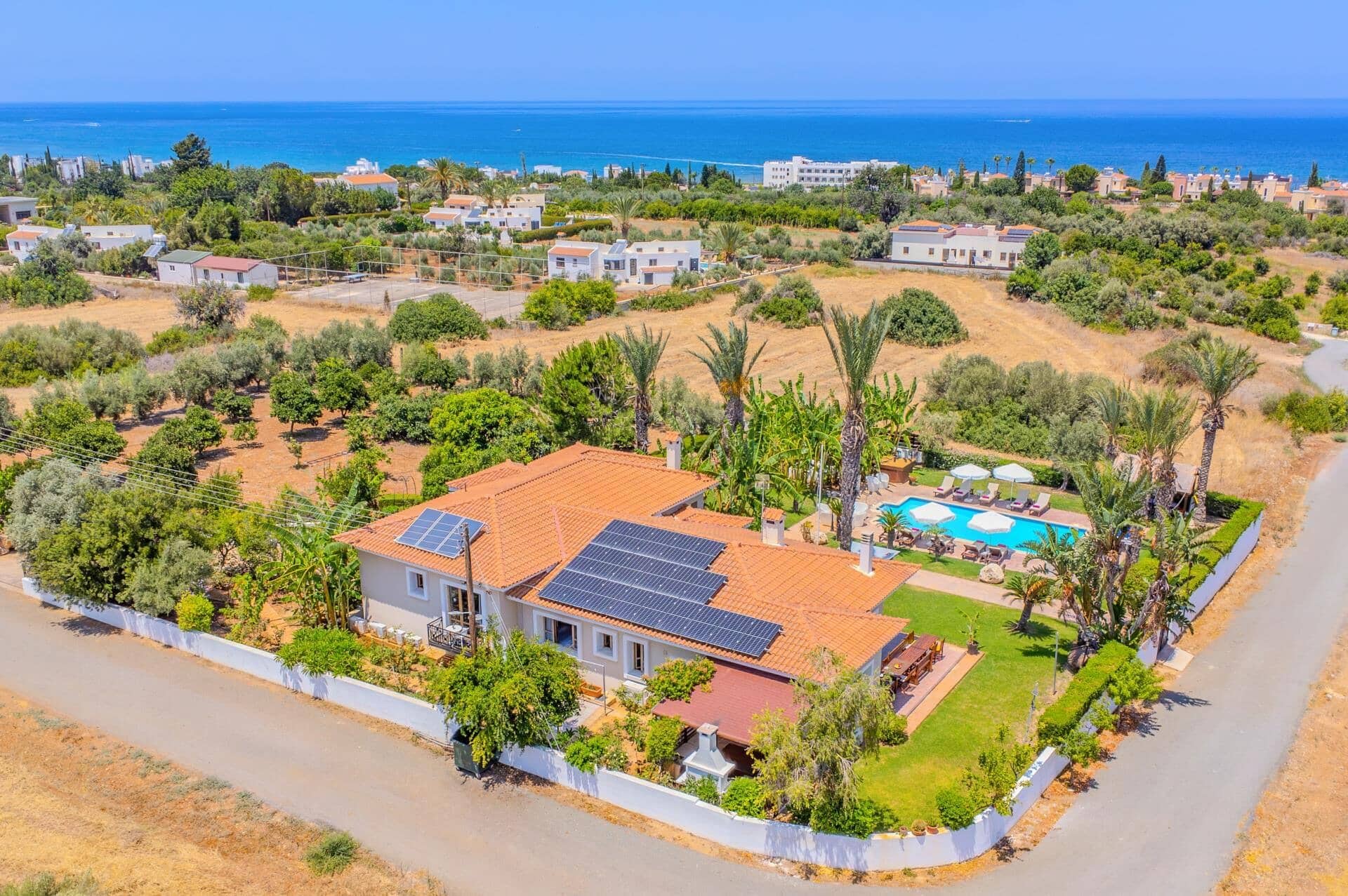 Un quartier résidentiel avec une maison dotée de panneaux solaires, d’une piscine et offrant une vue sur la mer.