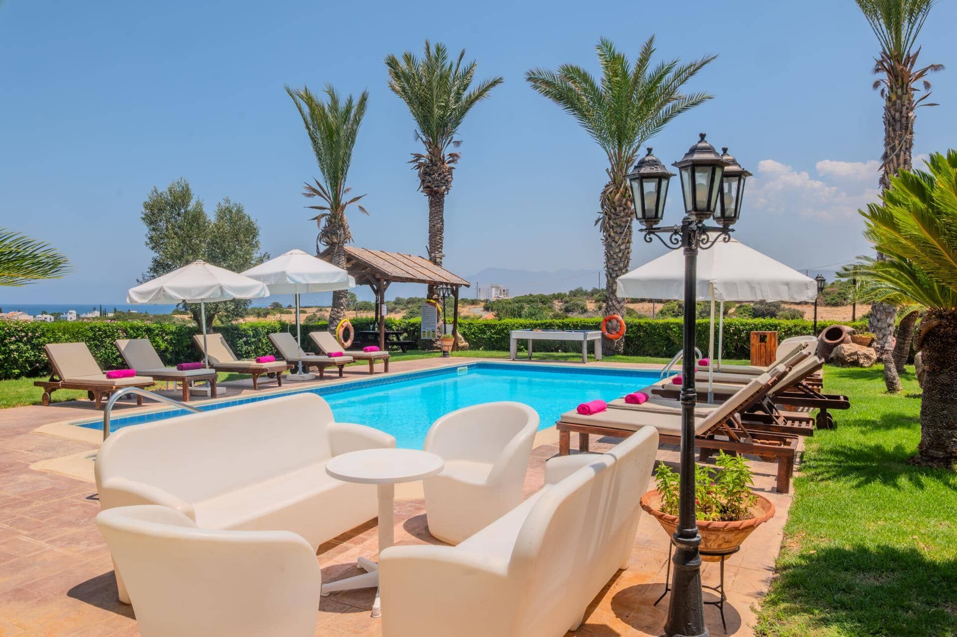 Ein Poolbereich mit Liegestühlen, Sonnenschirmen und Blick auf das Meer.