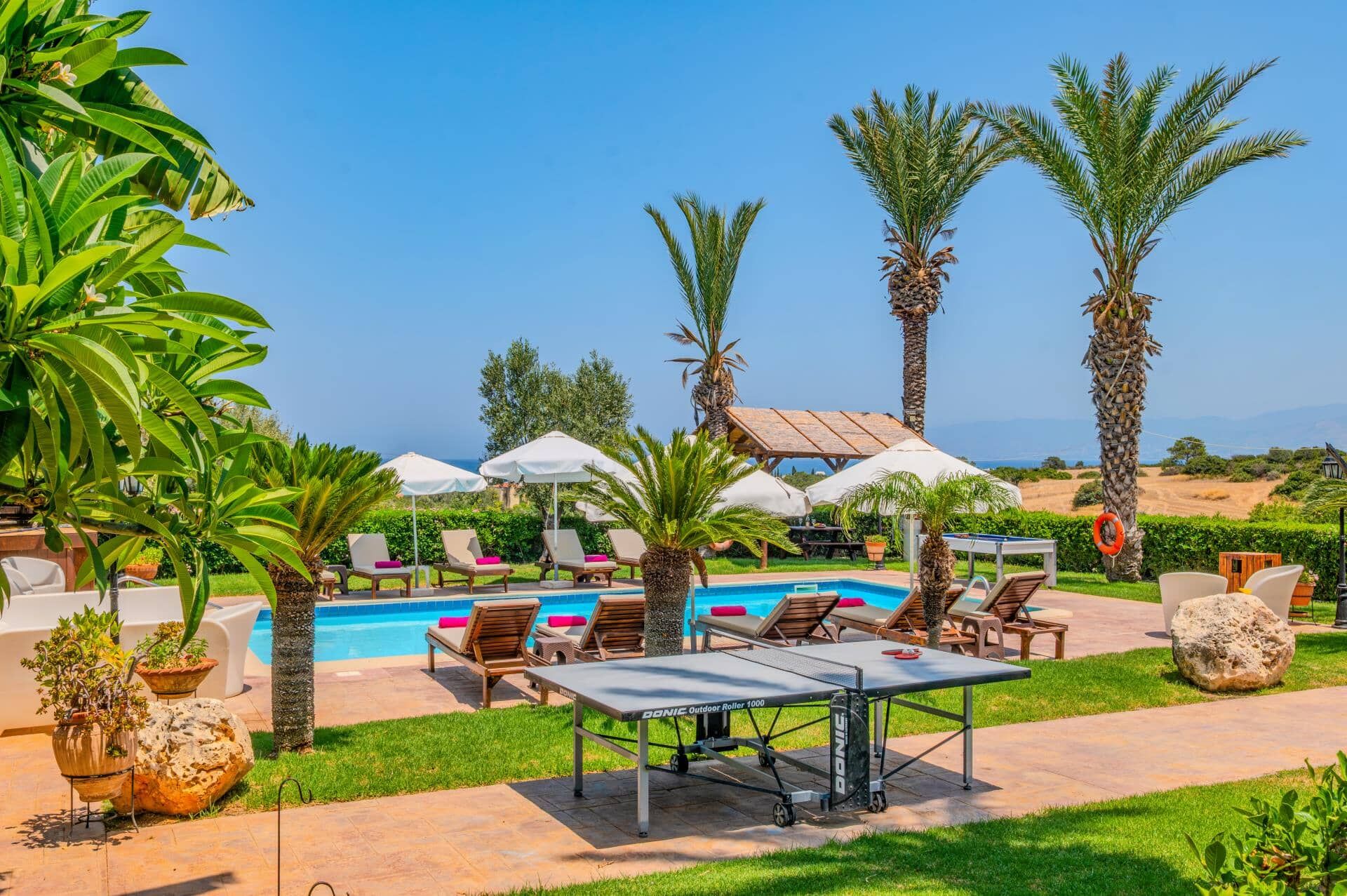 A poolside area with lounge chairs, umbrellas, and a table.