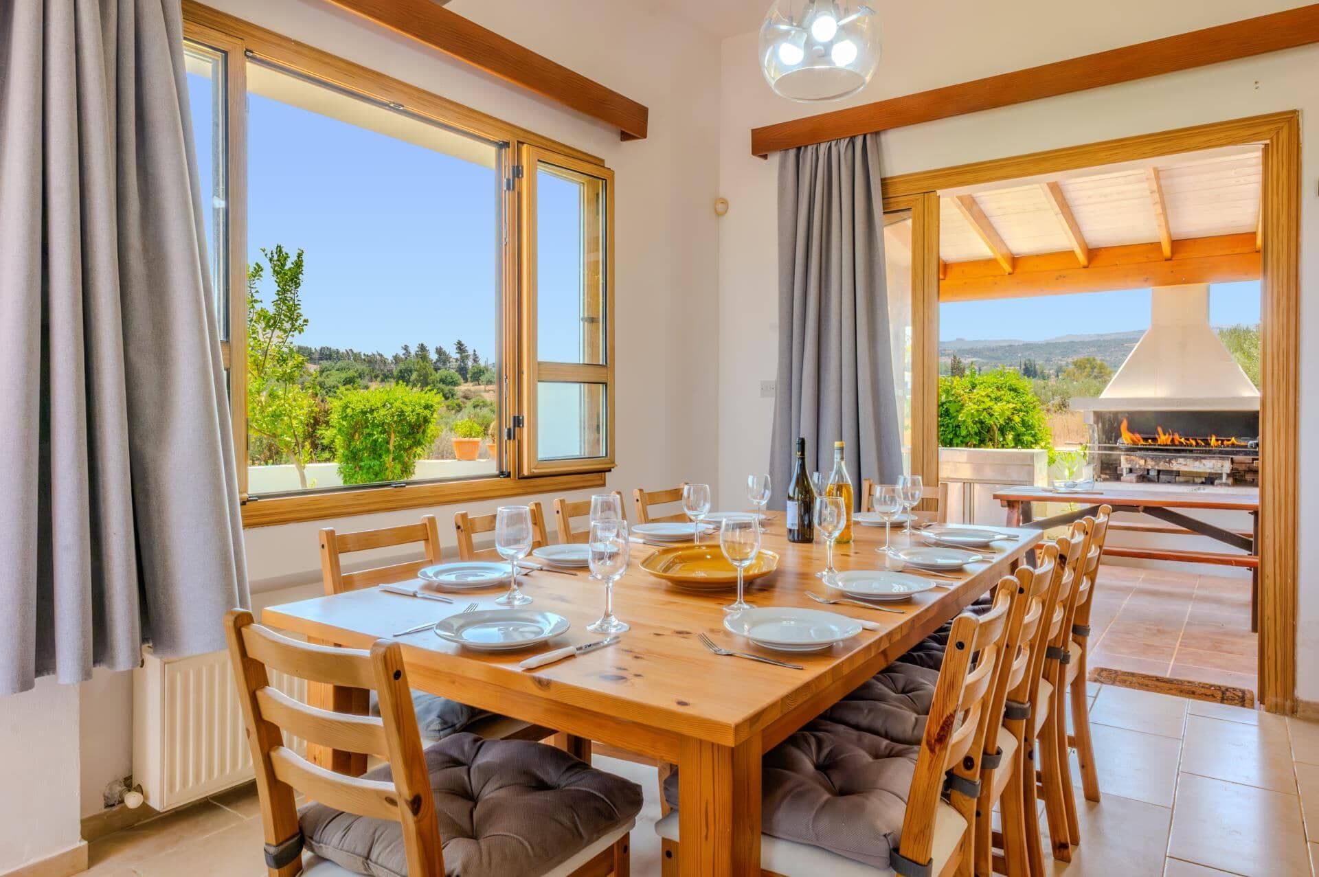 A dining area with a table set for four, large windows, and a view of a barbecue grill outside.