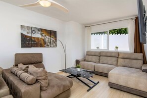 A living room with a sofa, a coffee table, a painting, and a window with curtains. - Villa Casa David by Villa Plus (Benalmadena)