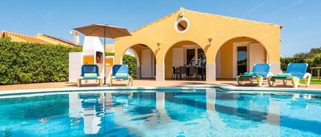 A pool area with lounge chairs and an outdoor seating area with tables and chairs.