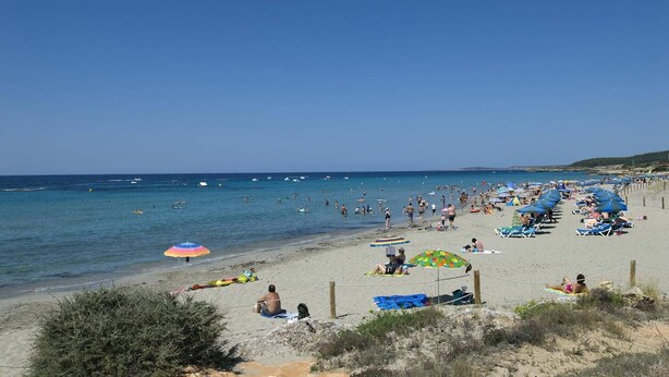 Une plage où l’on peut voir des gens se prélasser au soleil, nager et se promener le long du rivage.