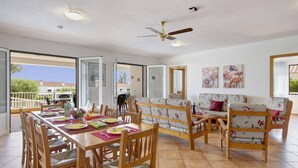 Un vaste espace de vie comprenant une table à manger pour quatre personnes, un canapé et un ventilateur de plafond.