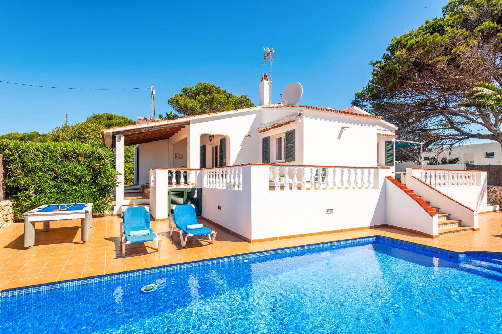 A white villa with a swimming pool, a covered patio, and a satellite dish.