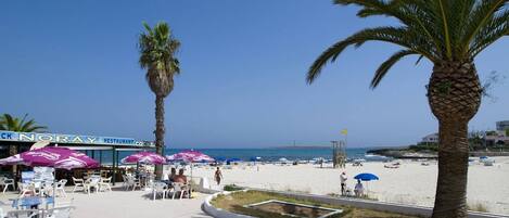 Een restaurant aan het strand met terras en palmbomen.
