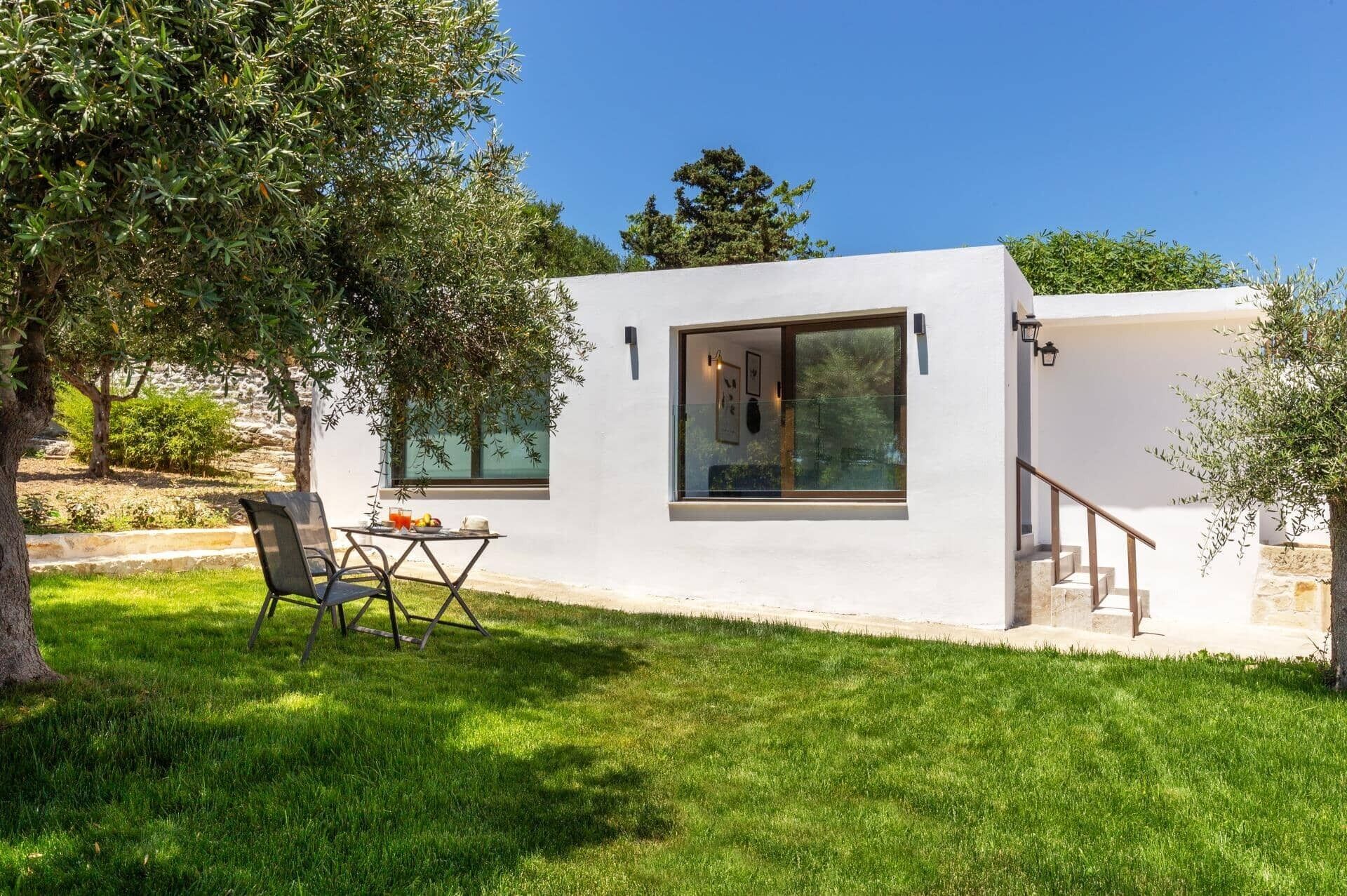 A modern house with a patio, a dining table with chairs, and a staircase leading to an upper level.