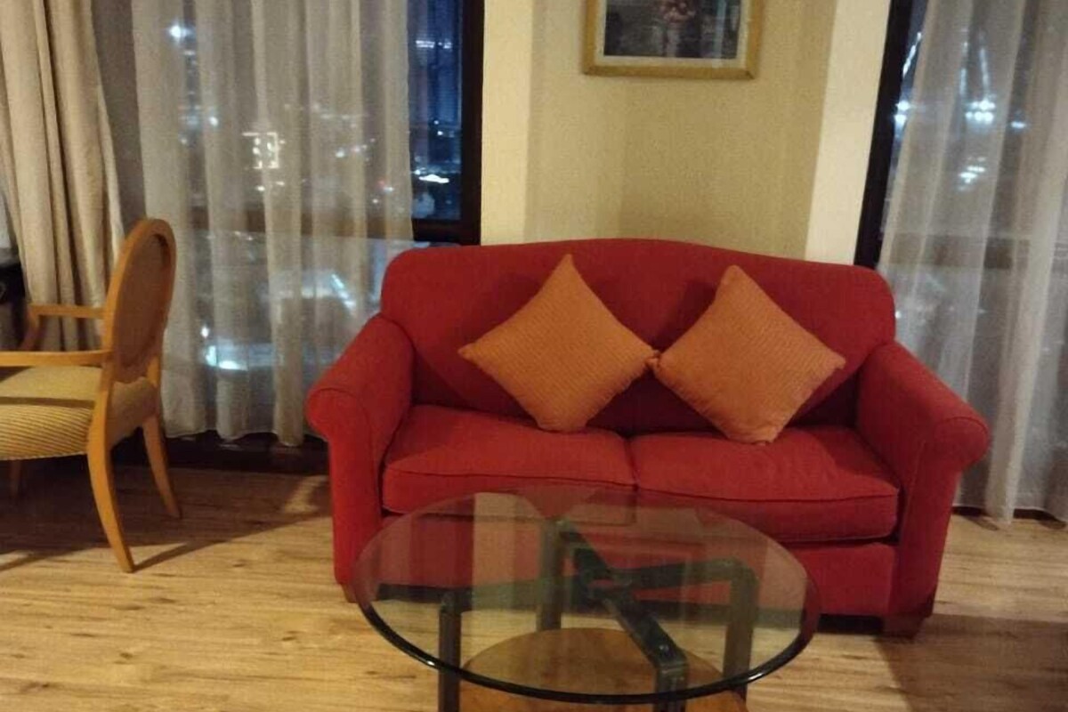 A living room with a red sofa, a glass coffee table, and a wooden chair.