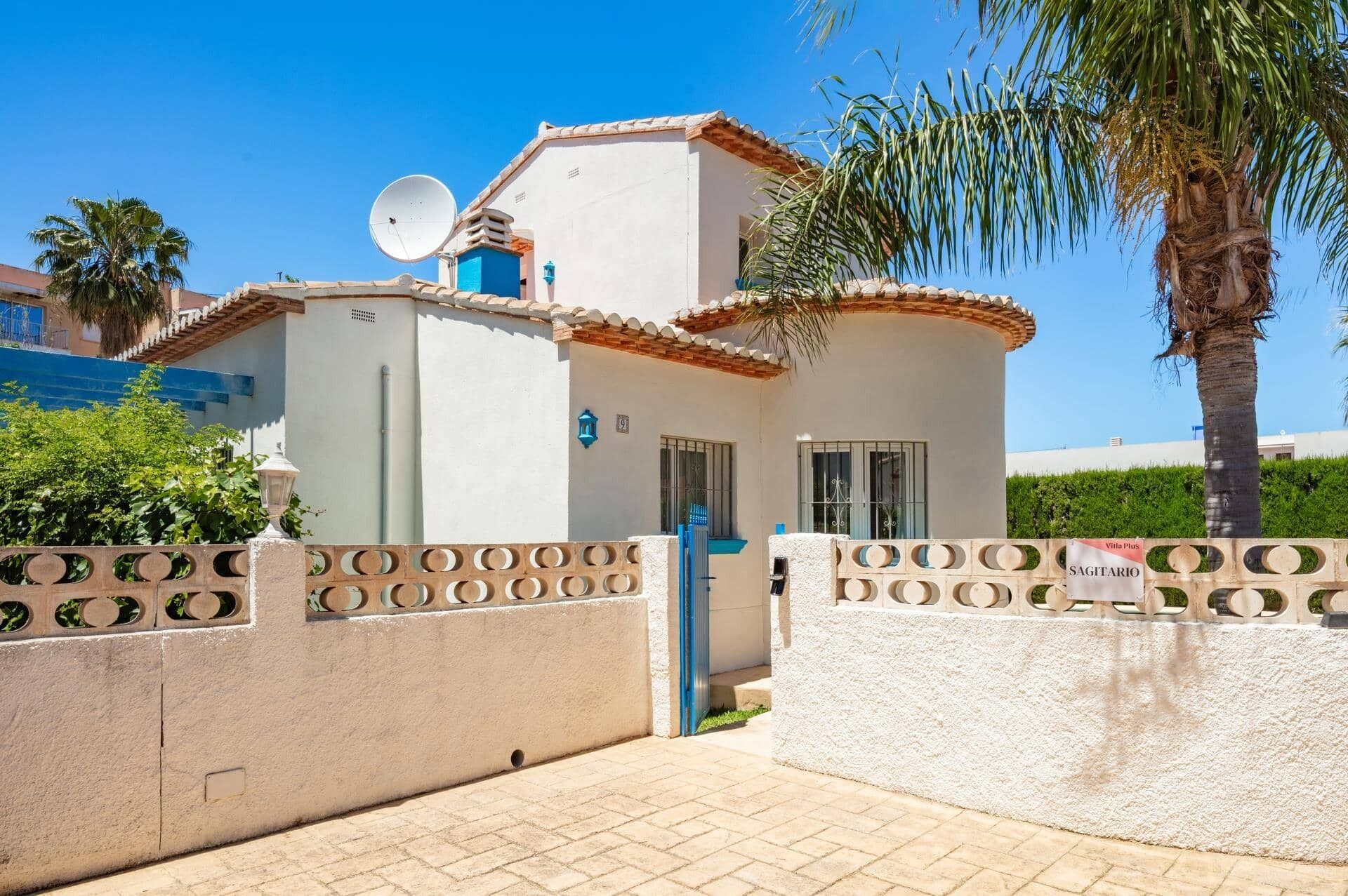 Un bâtiment à deux étages, doté d’une antenne parabolique, d’une porte bleue et d’un mur blanc orné d’un motif texturé.