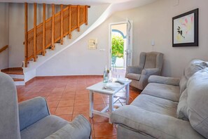 Ein Wohnzimmer mit Treppe, einem Esstisch mit Stühlen und einem gerahmten Bild an der Wand.