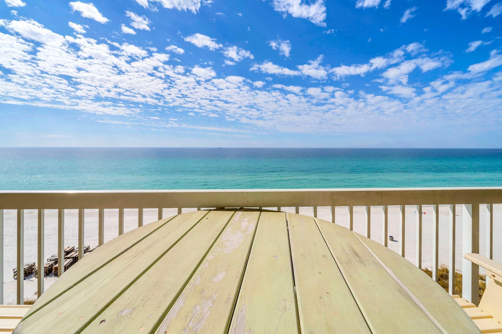 A wooden deck with a view of the ocean and beach.