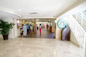 A spacious lobby with a Starbucks coffee shop, a reception desk, and a staircase. - Emerald Beach 1628 (Panama City Beach)