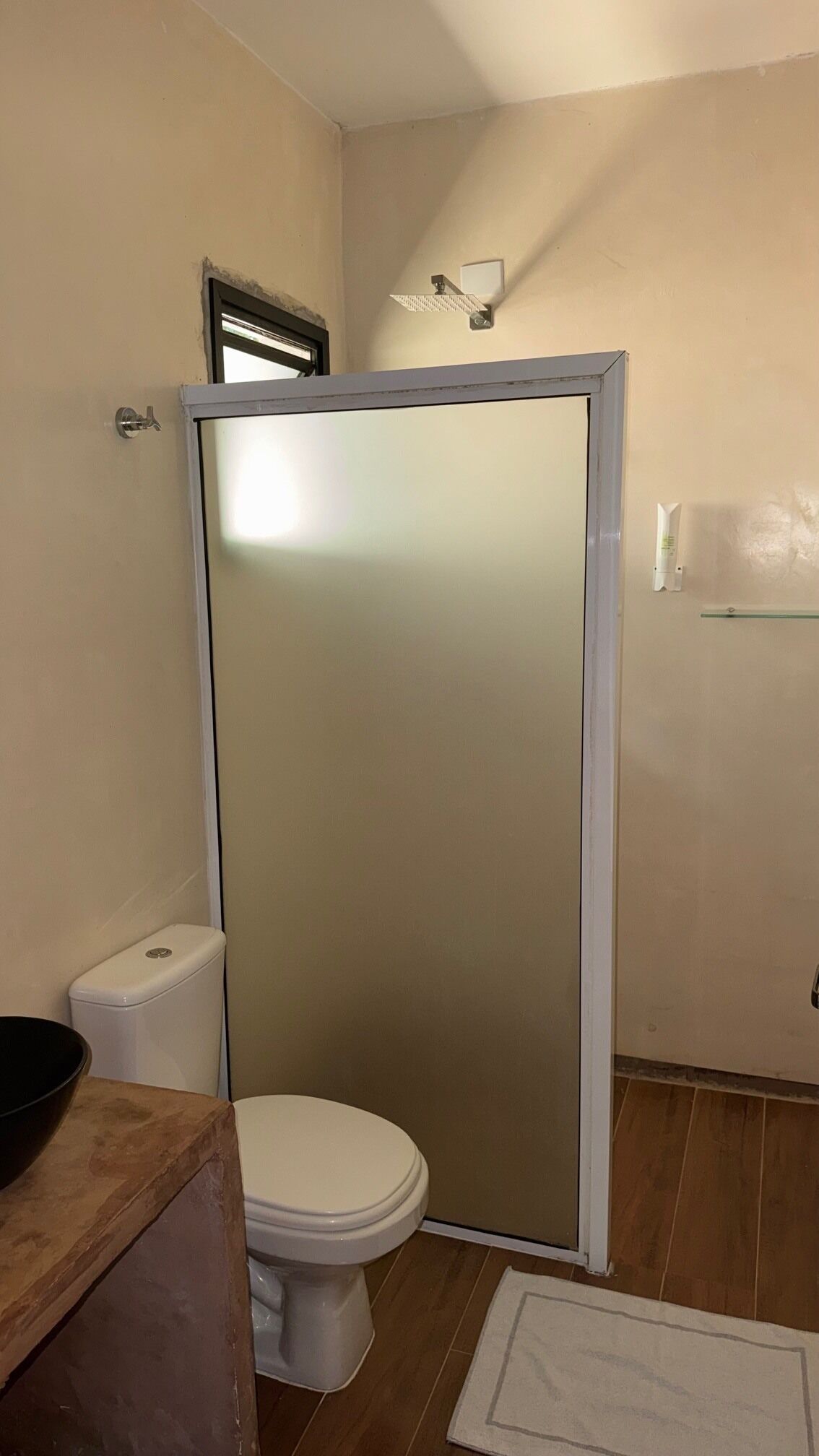 Un baño con inodoro, cabina de ducha y tocador de madera.