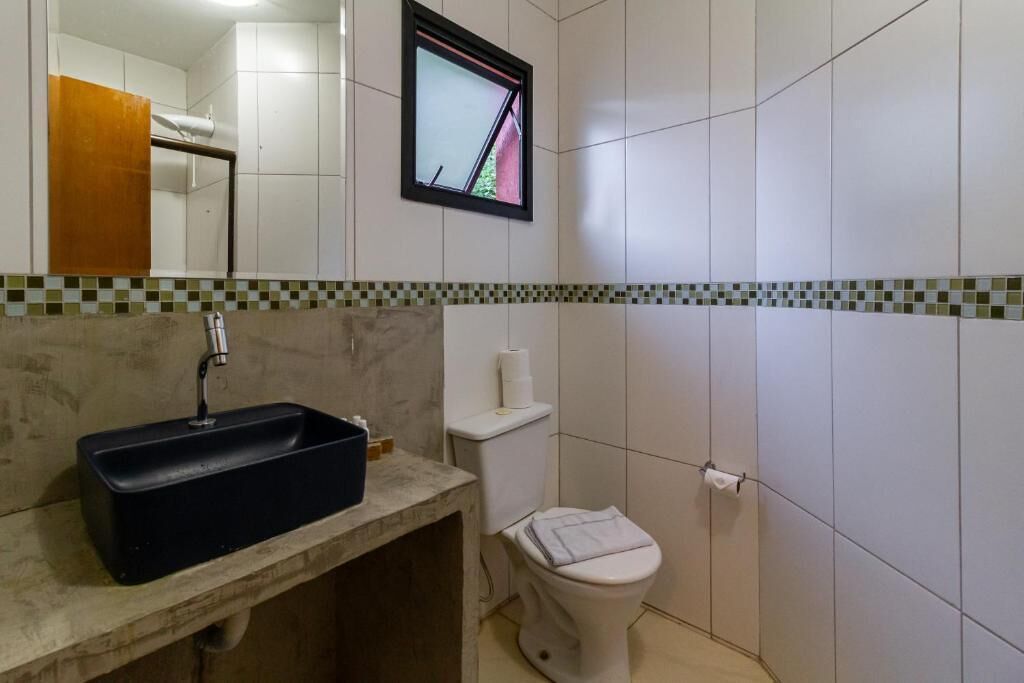 A bathroom with a black sink, white toilet, and a small window.