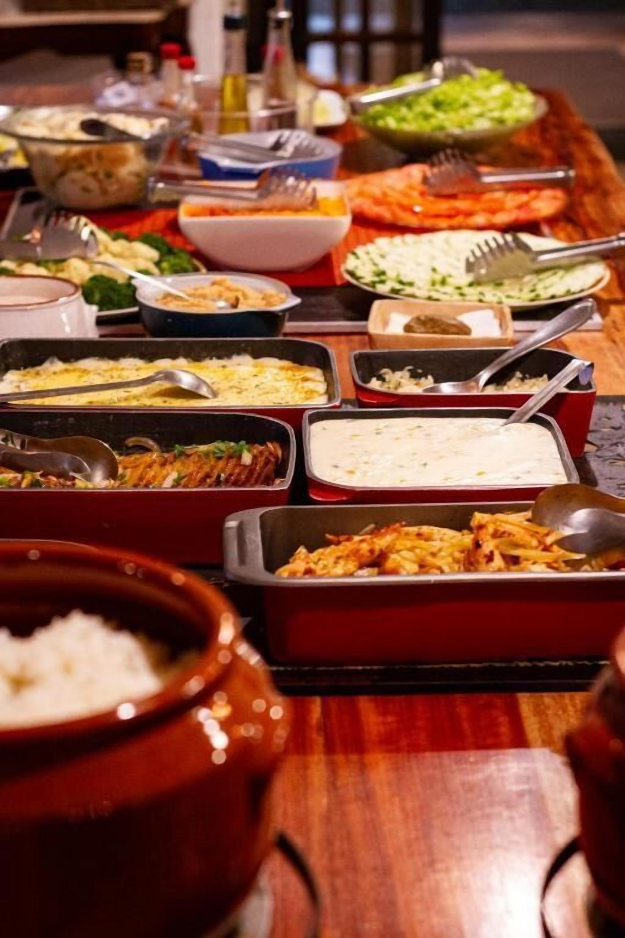 A buffet table with various dishes and utensils.