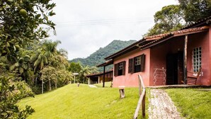 A red building with a paved pathway leading to a wooden door. - Pousada das Cavernas (Iporanga)