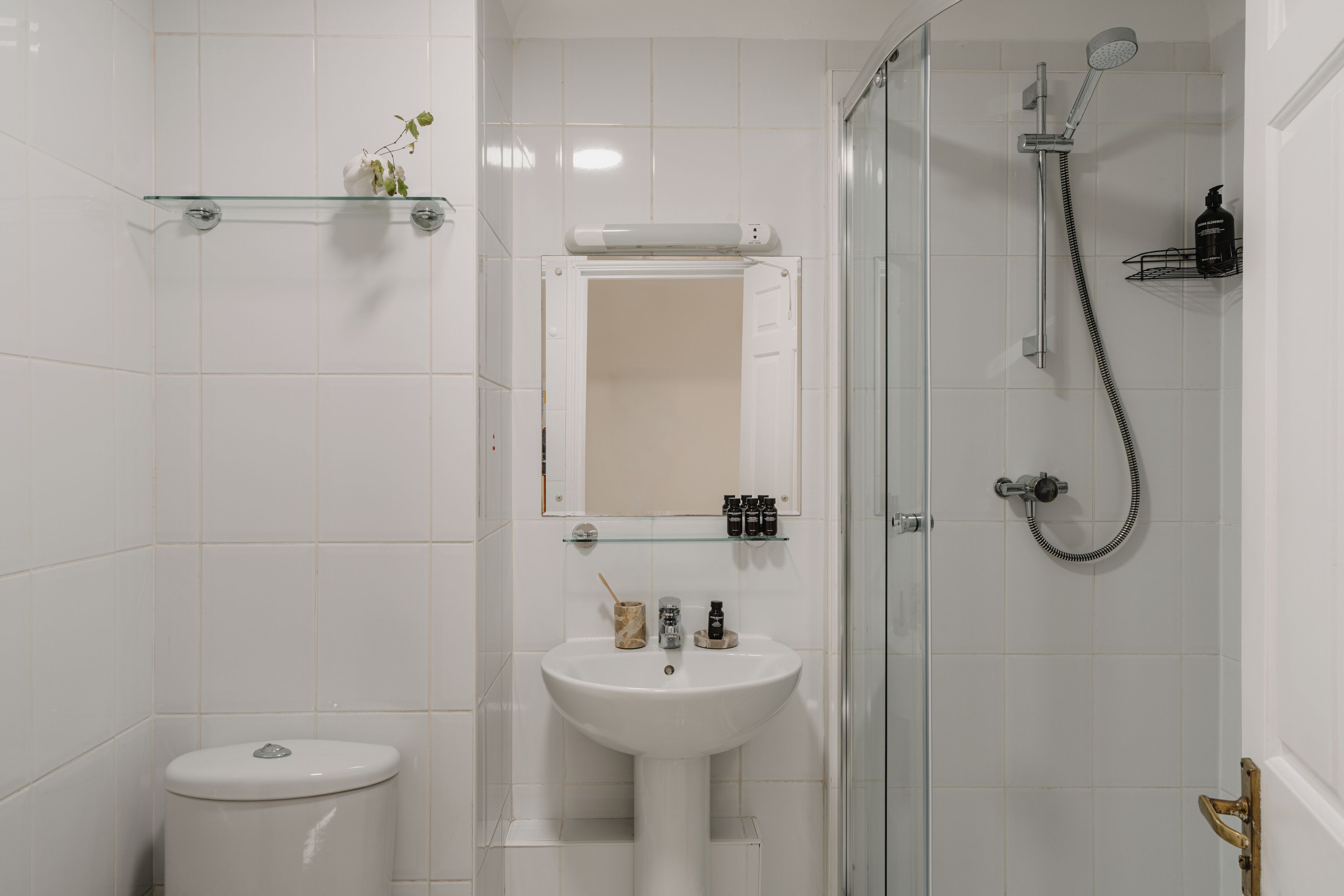 Et badeværelse med toilet, håndvask og brusekabine i glas.