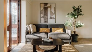 Ein Wohnzimmer mit grauem Sofa, einem Couchtisch, einer Zimmerpflanze und einem großen abstrakten Gemälde an der Wand.