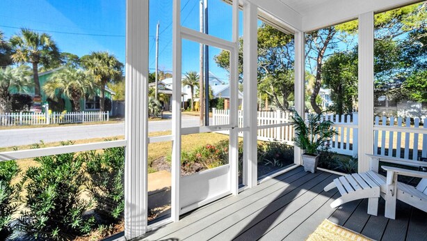 A covered porch with white railings, a bench, and potted plants. - The Grand Castle (Panama City Beach)