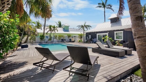 Una terraza de madera con sillones de descanso y una piscina.