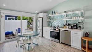 Una cocina compacta con armarios blancos, horno integrado y cafetera.