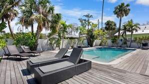 Un espace piscine avec des chaises longues et une terrasse en bois.