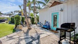 Une terrasse avec un barbecue, un vélo et une porte de couleur turquoise.