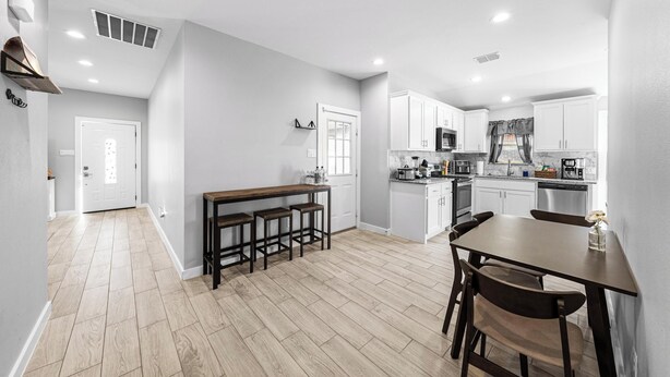A modern kitchen with white cabinets, a wooden dining table, and a built-in oven. - Luxury Remodeled 3 Bed/2 Bath Home with Patio Deck (Mansfield)